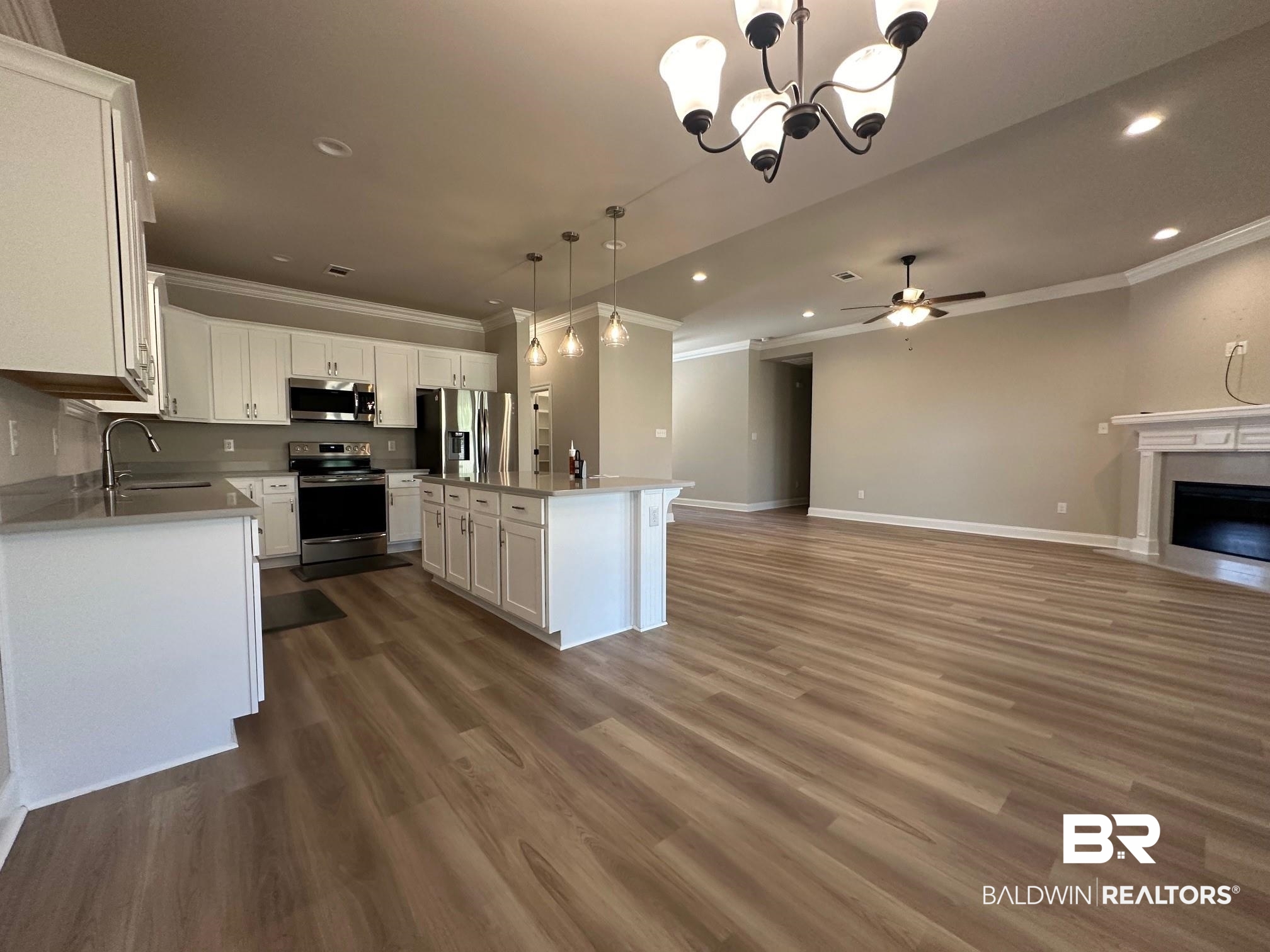 1009 Ruisseau Drive Foley, AL 36535 - Photo 34 of 55 Kitchen featuring appliances with stainless steel finishes, a kitchen island, hanging light fixtures, white cabinetry, and dark hardwood / wood-style floors