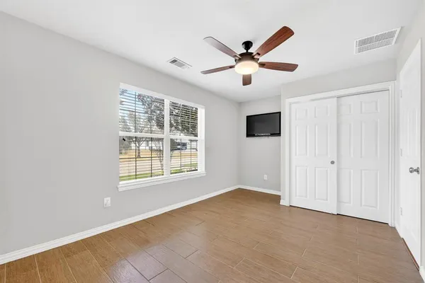 a view of an empty room with window and chandelier fan