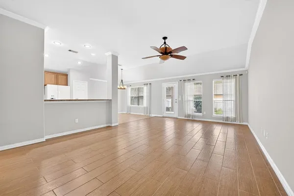 a view of an empty room with wooden floor and a window