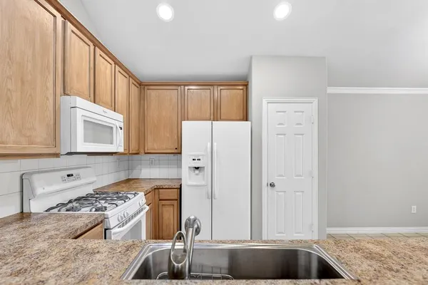 a kitchen with stainless steel appliances granite countertop a refrigerator sink and stove