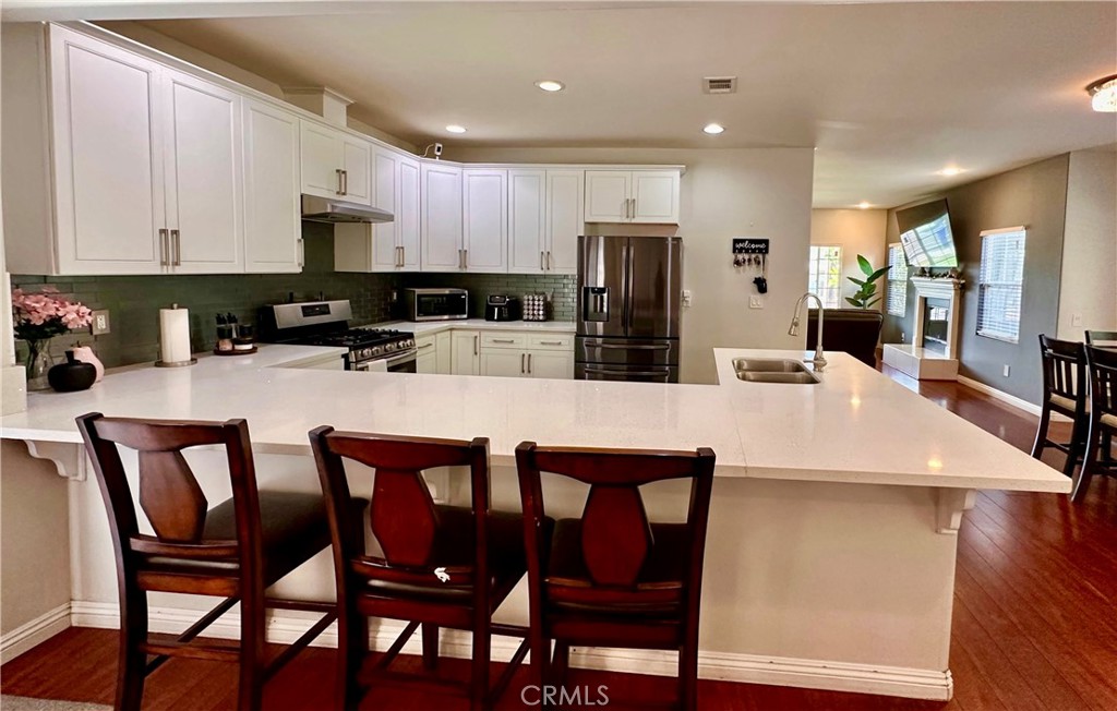 514 West Randall Avenue Rialto, CA 92376 - Photo 7 of 19 a kitchen with stainless steel appliances kitchen island granite countertop a table chairs microwave and sink