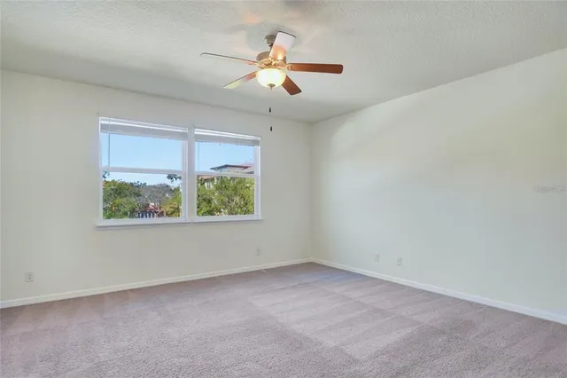 an empty room with windows and ceiling fan