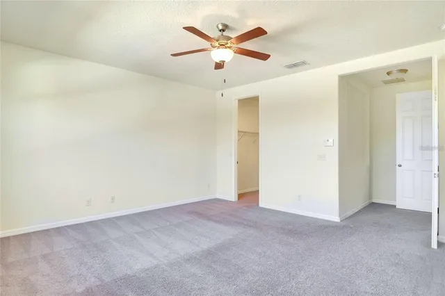 an empty room with ceiling fan and window