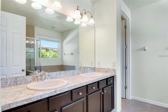a bathroom with a granite countertop double vanity sink and a mirror