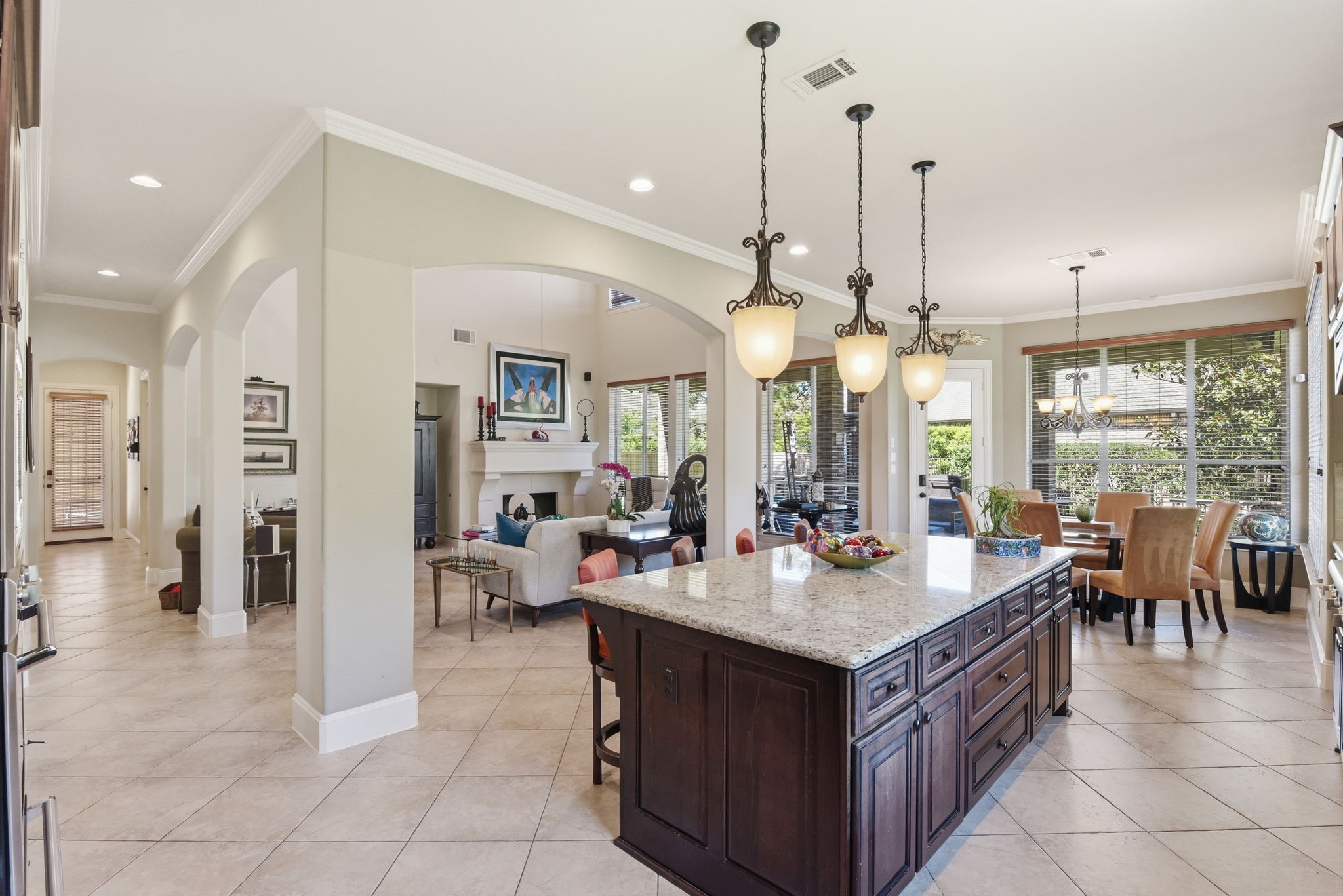 223 South Bauer Point Circle Spring, TX 77389 - Photo 17 of 50 This open-concept living space features a spacious kitchen with a large island, elegant pendant lighting, and ample cabinet storage. Adjacent is a cozy living room with a fireplace and a dining area with large windows offering abundant natural light. The room's neutral tones and tiled floor create a warm, inviting atmosphere.