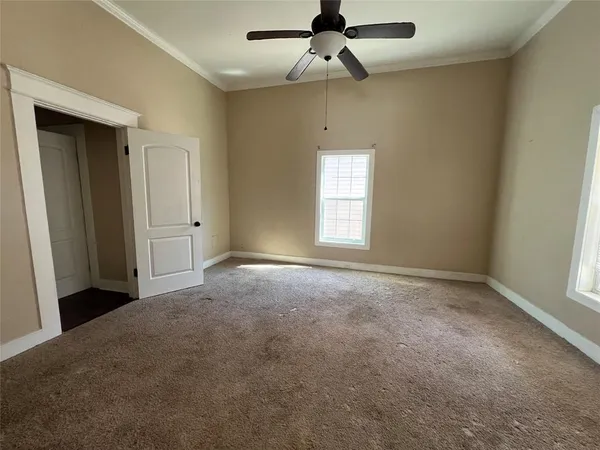 an empty room with windows and fan