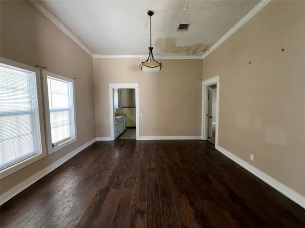 a view of an empty room with wooden floor fridge and a window