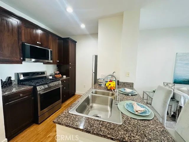 a kitchen with stainless steel appliances granite countertop a sink a stove a microwave and wooden cabinets