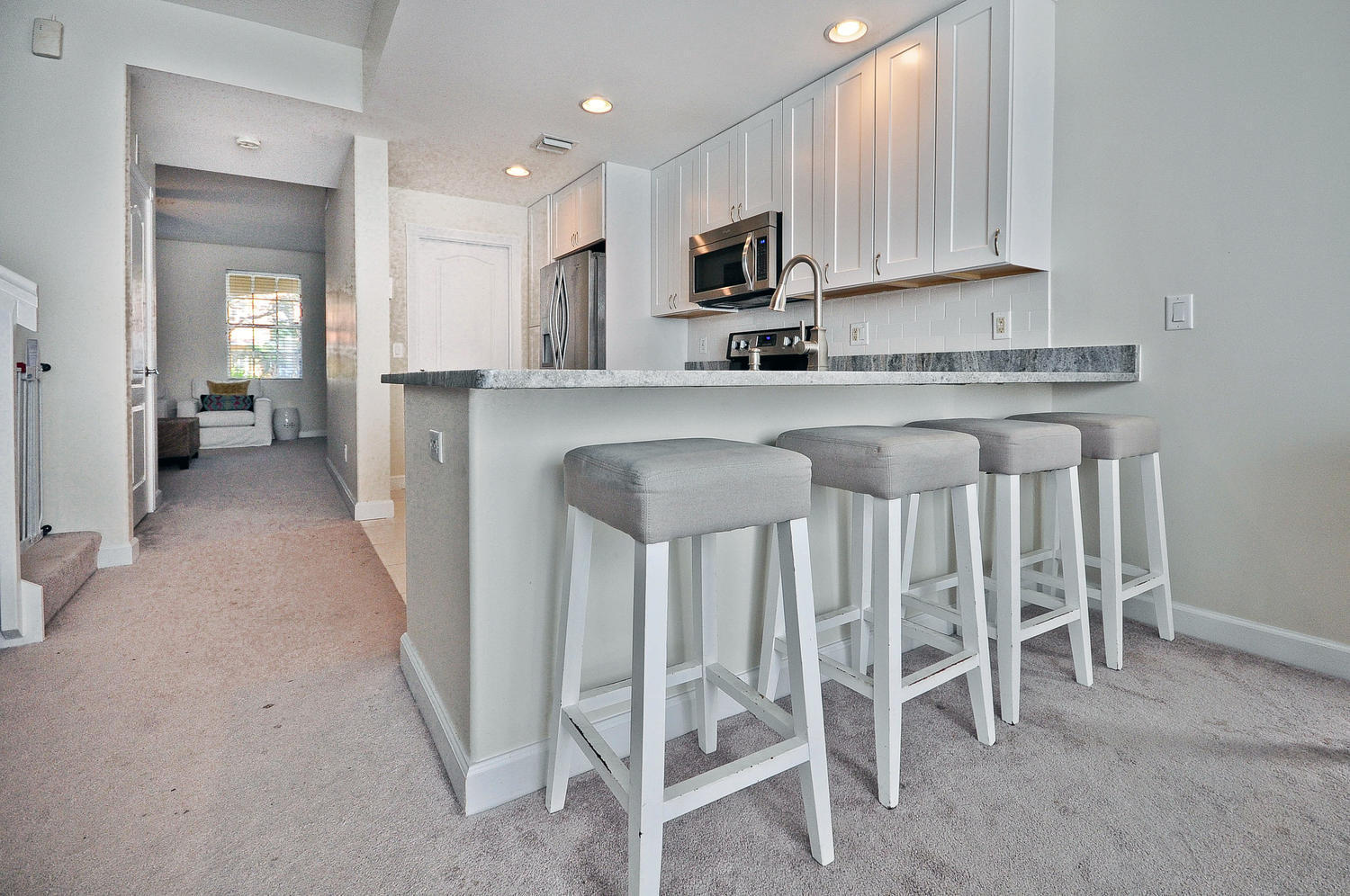 4135 Community Drive Jupiter, FL 33458 - Photo 11 of 39 a kitchen with white cabinets and chairs