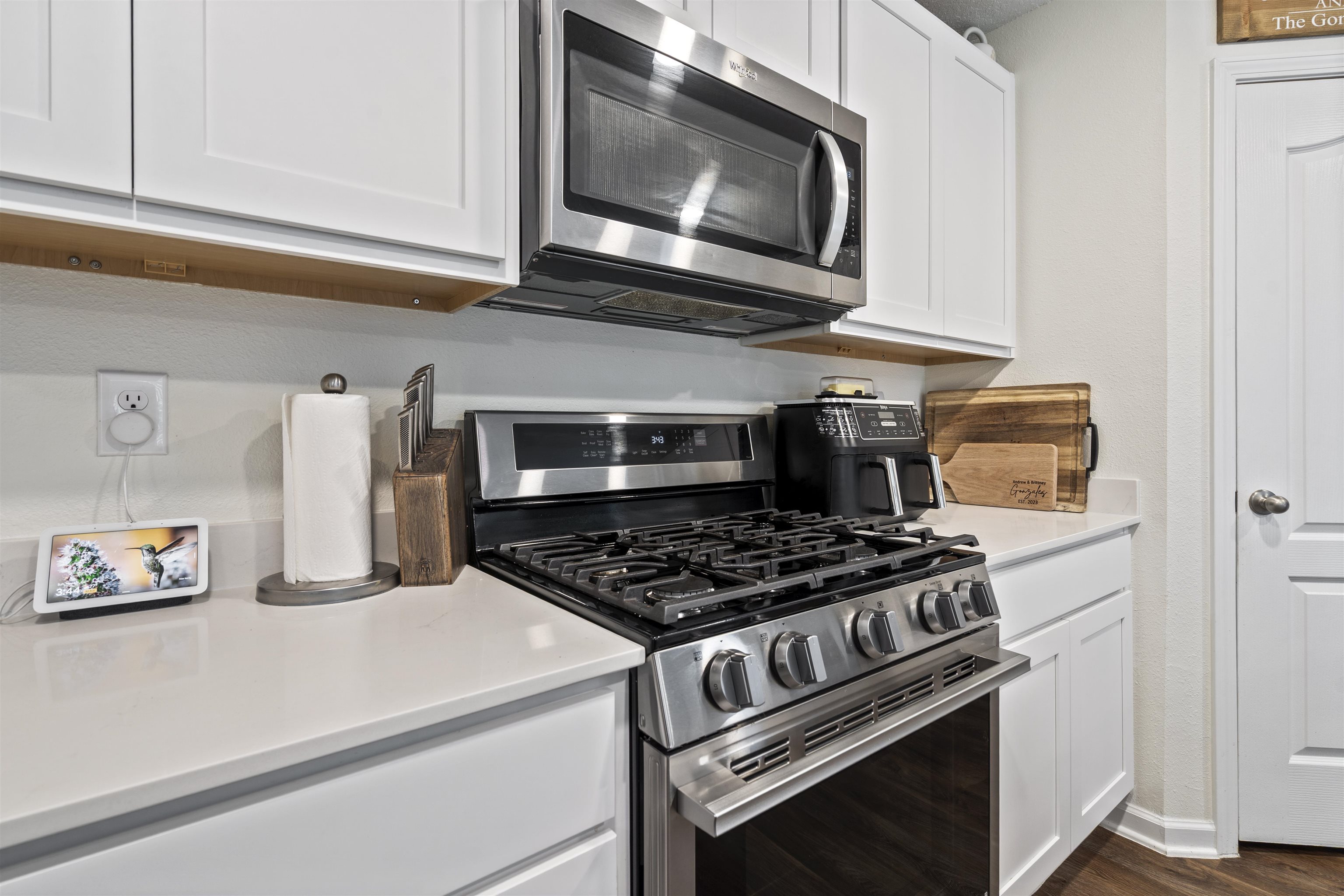 127 Encanto Way St. Augustine, FL 32084 - Photo 13 of 43 a kitchen with stainless steel appliances granite countertop white cabinets a stove a microwave and wooden floors