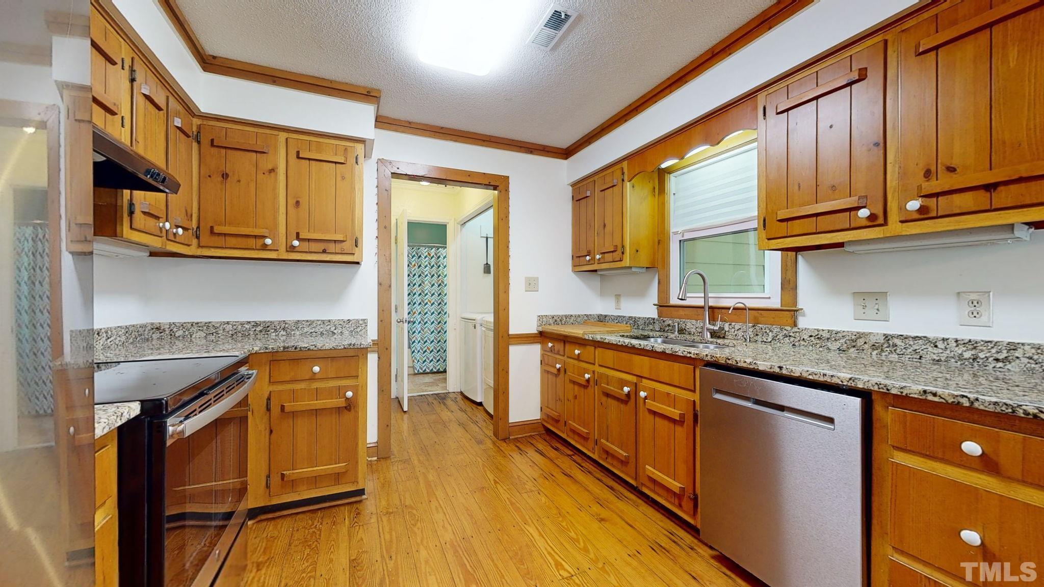 3308 Gatcombe Place Raleigh, NC 27604 - Photo 12 of 43 a kitchen with stainless steel appliances granite countertop wooden cabinets a sink and dishwasher a stove with wooden floor