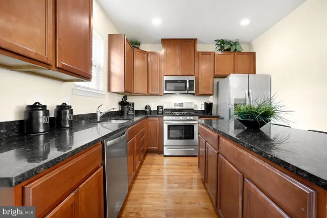 a kitchen with stainless steel appliances granite countertop a sink a stove and a refrigerator