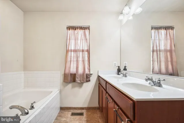 a bathroom with a tub sink and mirror