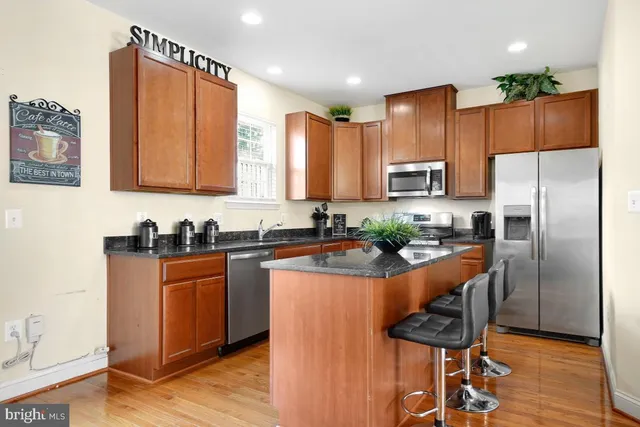 a kitchen with stainless steel appliances granite countertop a refrigerator a stove a sink a dining table and chairs