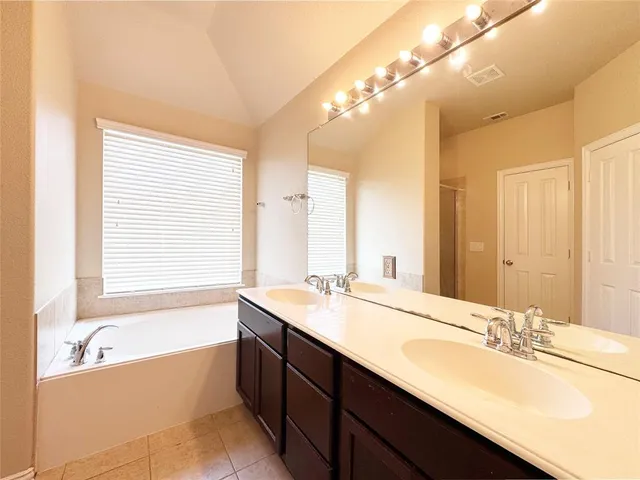a bathroom with a tub sink and mirror