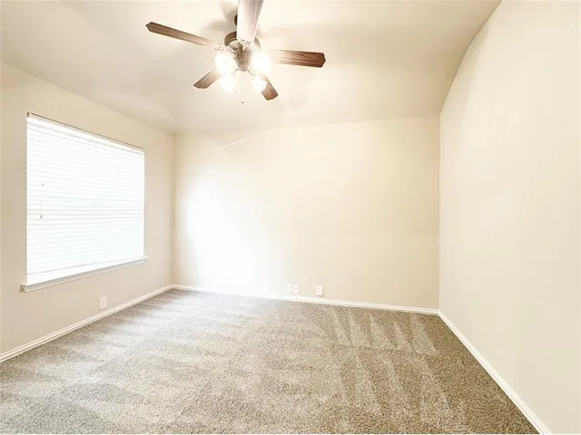 an empty room with a window and a ceiling fan
