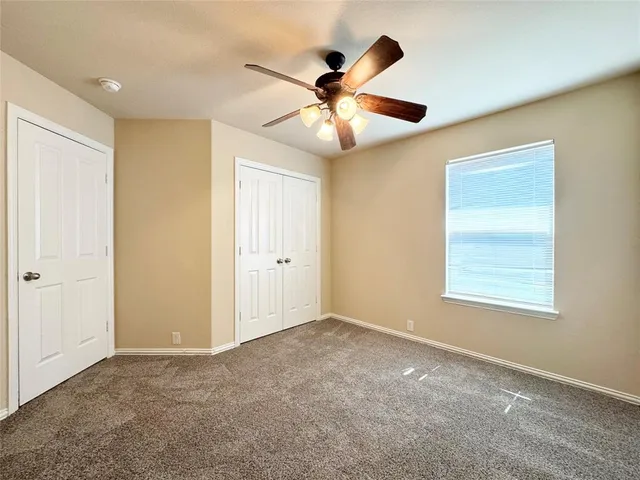 a view of an empty room with window and a ceiling fan