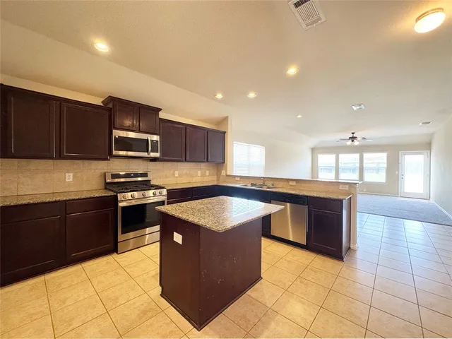 a kitchen with stainless steel appliances granite countertop a stove top oven a sink a counter top space and cabinets
