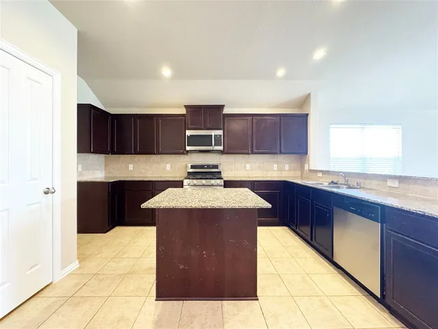 a kitchen with kitchen island granite countertop wooden cabinets and granite counter tops