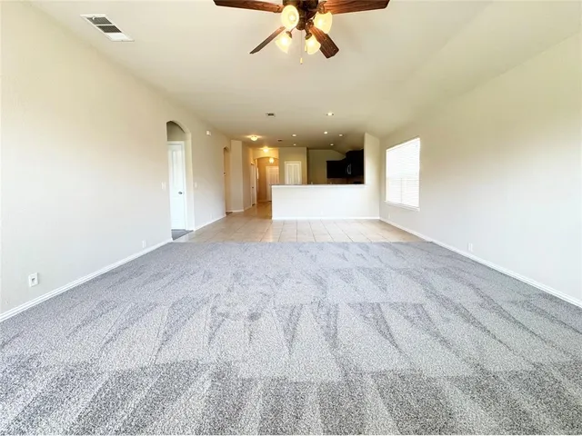 an empty room with a chandelier fan and windows