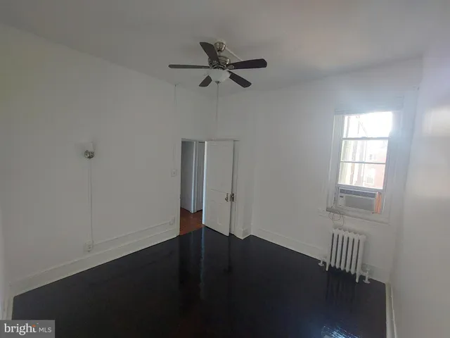 an empty room with wooden floor fan and windows
