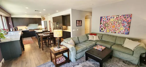 a living room with furniture kitchen view and a wooden floor