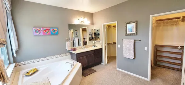 a spacious bathroom with a tub sink and mirror