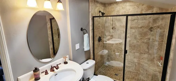 a bathroom with a toilet sink vanity and shower
