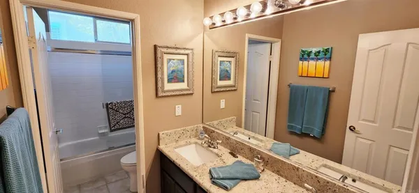 a bathroom with a granite countertop sink a mirror and a shower