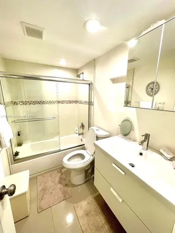 a bathroom with a double vanity sink toilet mirror and shower
