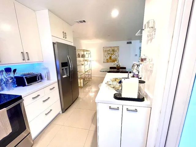 a kitchen with stainless steel appliances a stove a refrigerator a sink a counter top space and cabinets