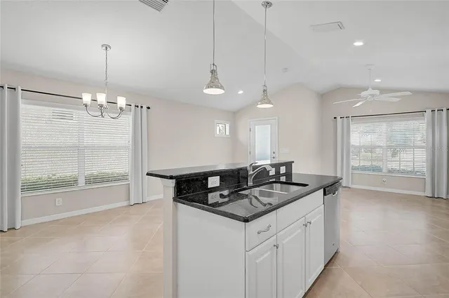 a kitchen with stainless steel appliances granite countertop a stove a refrigerator a sink a microwave and white cabinets