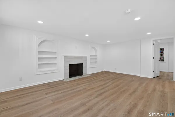 a view of empty room with wooden floor and fireplace