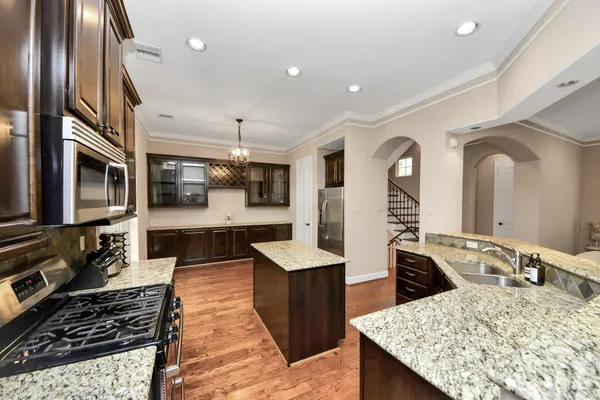 a large kitchen with stainless steel appliances granite countertop a lot of counter space and wooden floor