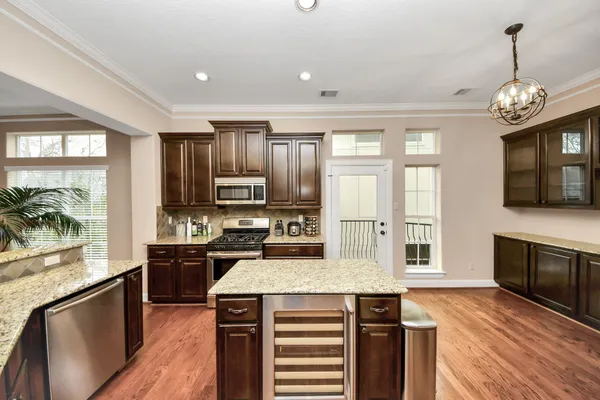 a kitchen with stainless steel appliances granite countertop a stove top oven a sink dishwasher a dining table and chairs with wooden floor