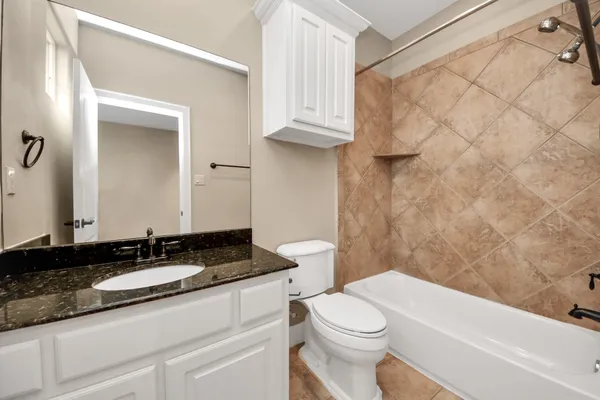 a bathroom with a granite countertop sink a toilet and a bathtub