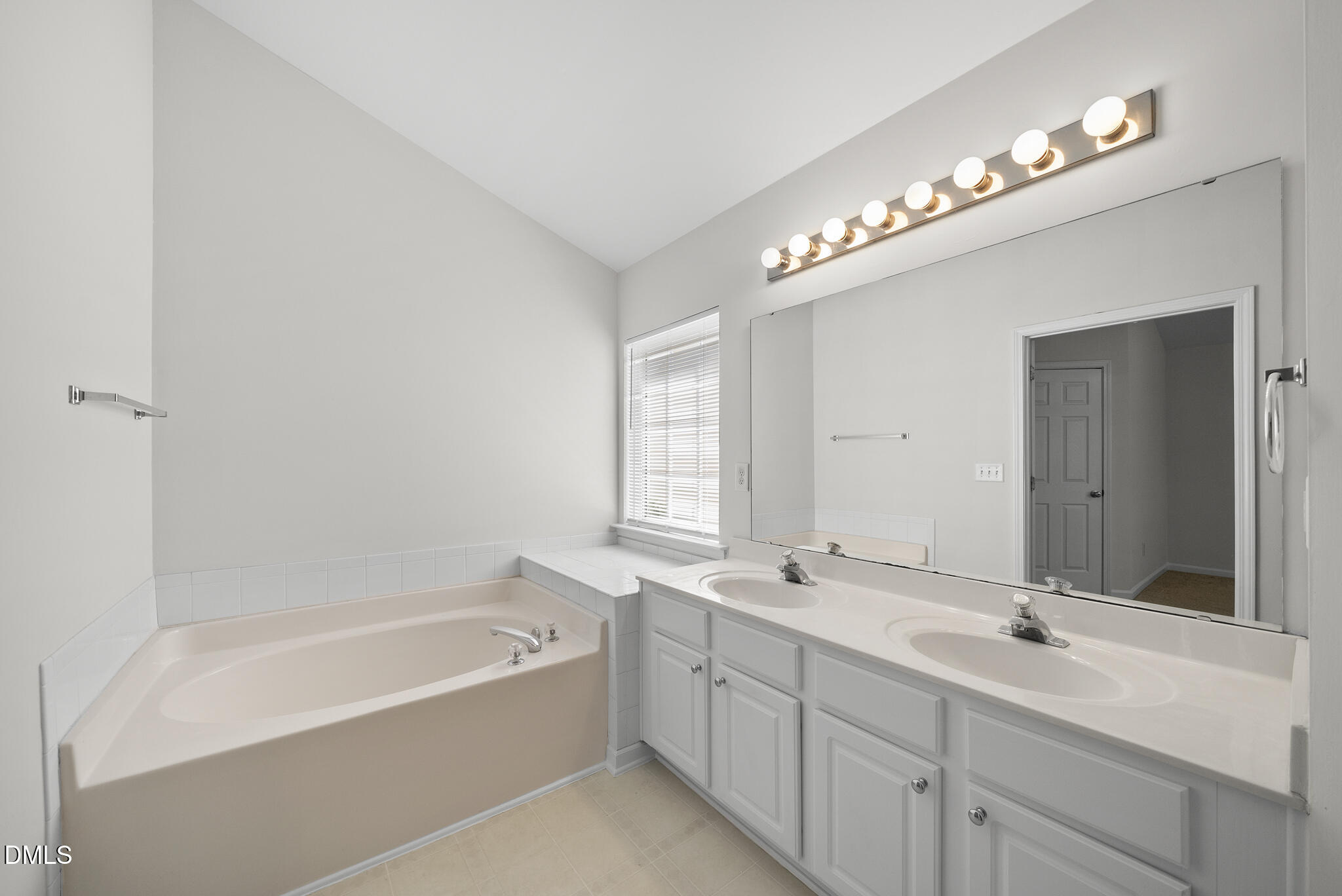 1024 Goldmist Lane Durham, NC 27713 - Photo 21 of 46 a bathroom with a tub a double vanity sink and a mirror
