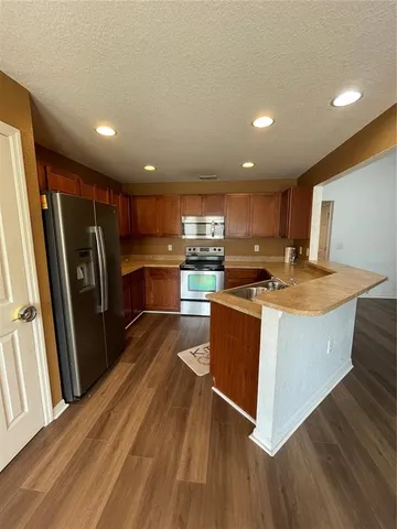 a kitchen with stainless steel appliances granite countertop a refrigerator a stove and a sink