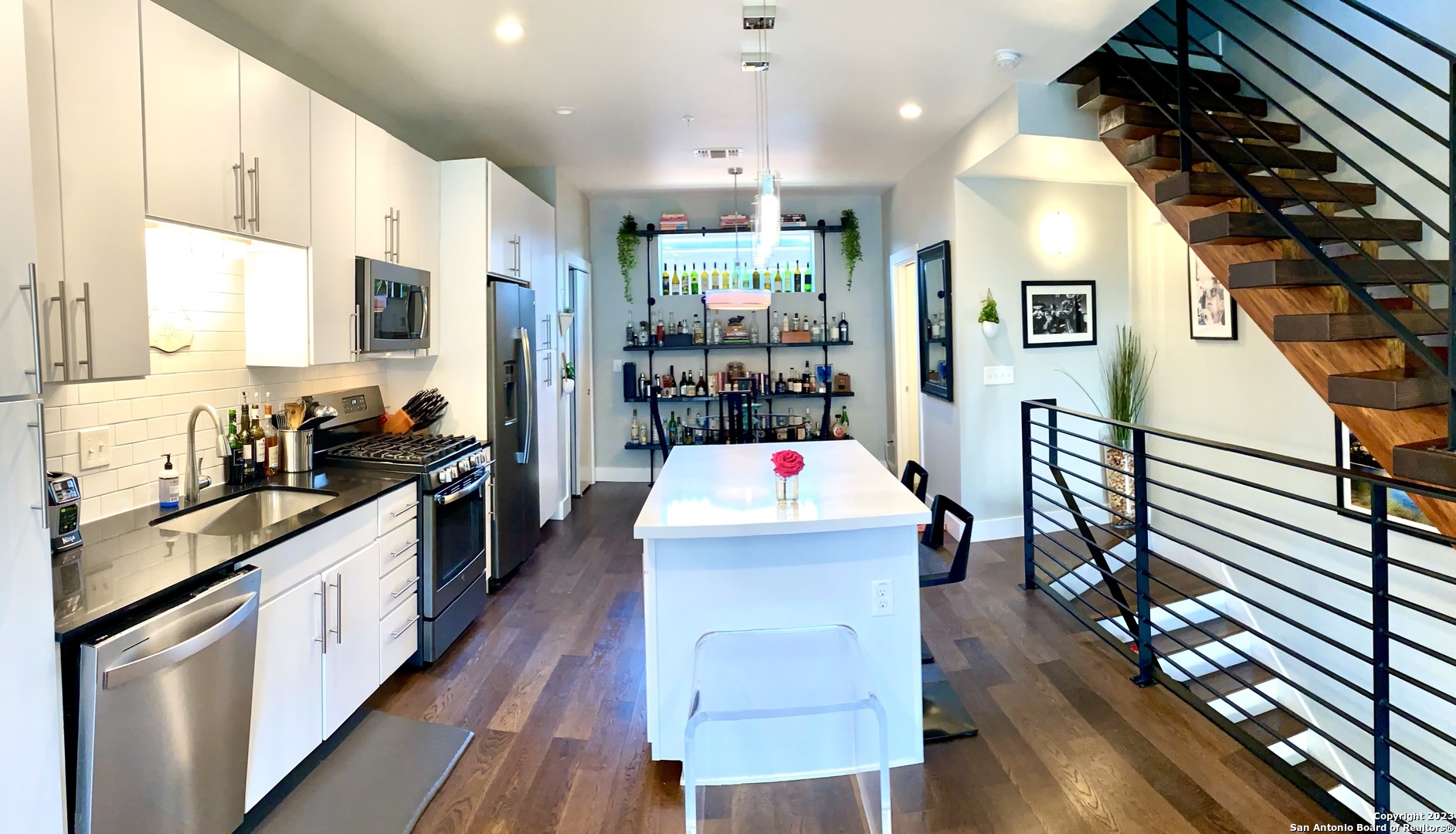 a large white kitchen with wooden floor and stainless steel appliances