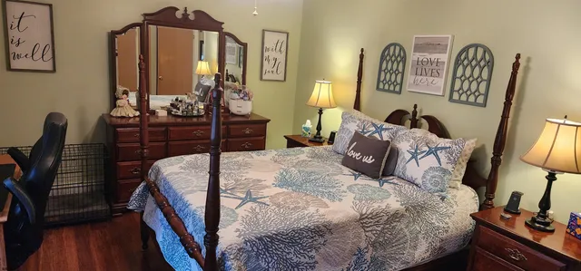 a bedroom with a bed a dresser and mirror