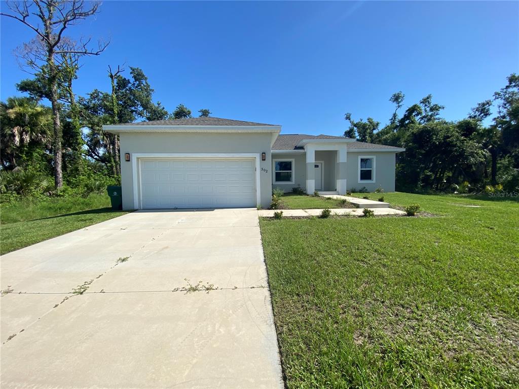 a view of a white house with a yard and sitting area