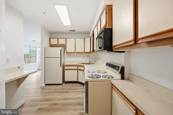 a kitchen with a refrigerator a stove top oven a sink and cabinets