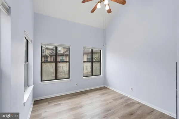 an empty room with chandelier fan and windows