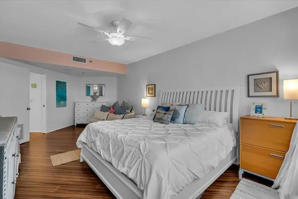 a bedroom with a bed and a dresser with wooden floor