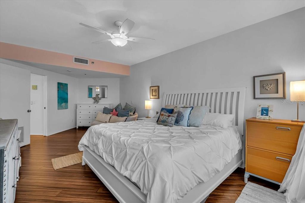 5621 Gulf Of Mexico Drive, Unit 102 Longboat Key, FL 34228 - Photo 15 of 22 a bedroom with a bed and a dresser with wooden floor