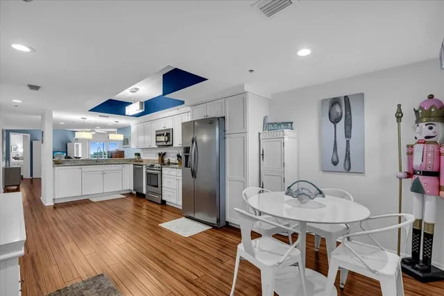 a kitchen with stainless steel appliances kitchen island granite countertop a sink refrigerator and cabinets