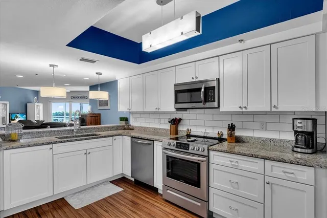 a kitchen with granite countertop a sink stainless steel appliances and white cabinets