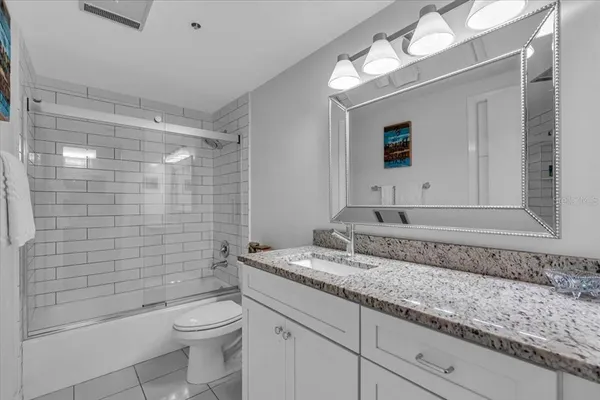 a bathroom with a granite countertop sink a toilet and shower