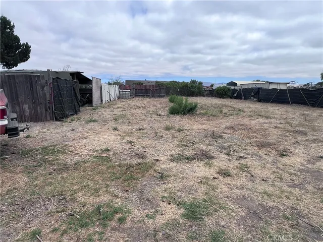 a view of a dry yard with wooden fence
