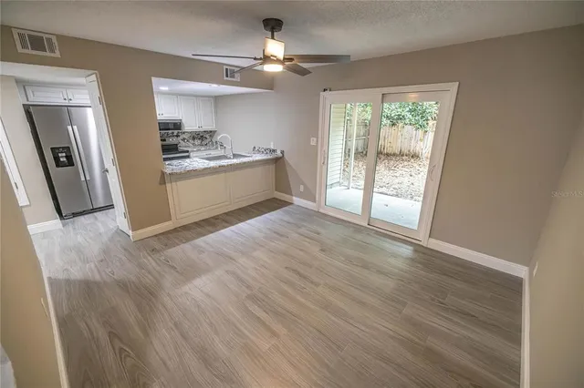 a view of kitchen and empty room with wooden floor